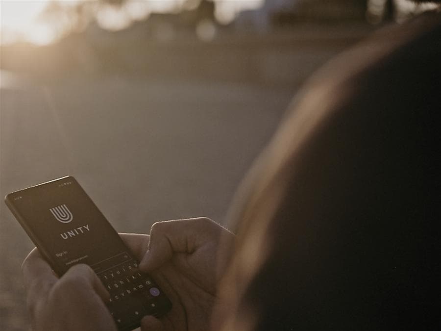 A person signing in to the Unity app on their phone at sunset
